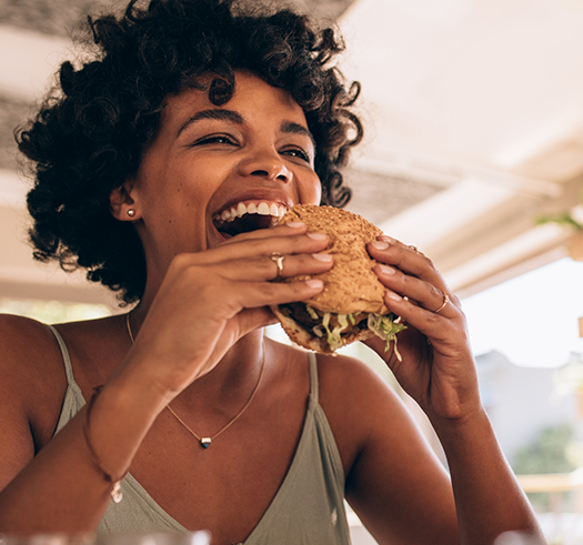 Smiling woman biting into a burger