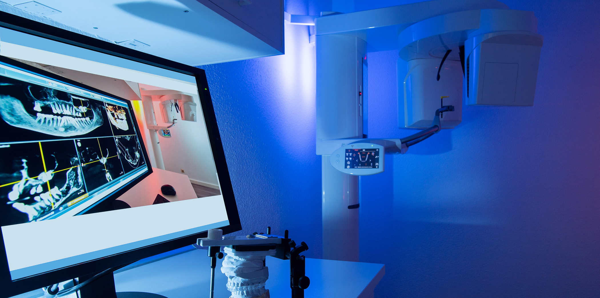 Dental lab with a scanning device and a screen showing digital models and x rays of teeth