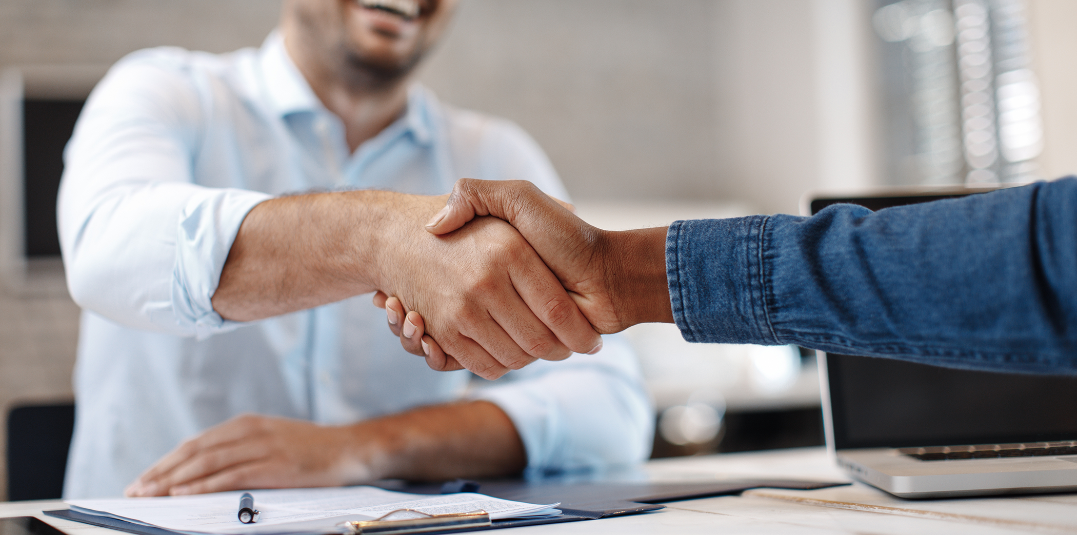 Dental patient shaking hands with their dentist across a table