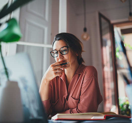 Woman sitting at a desk and looking closely at a laptop