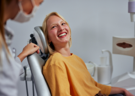 Dental patient in a yellow sweater smiling at her dentist in Bartlett