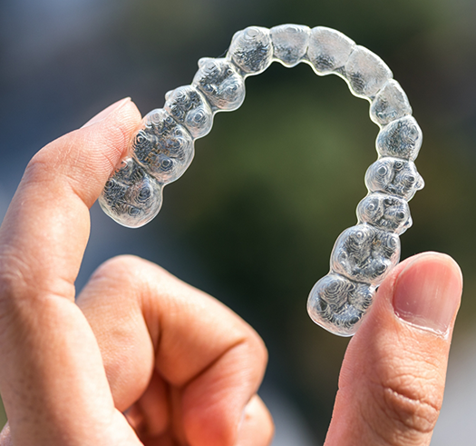 Hand holding an Invisalign clear aligner
