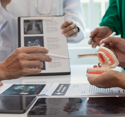Group of people sitting at a table and looking at a model of the teeth together