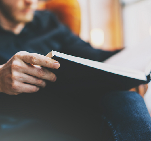 Man sitting in an armchair and reading a black book