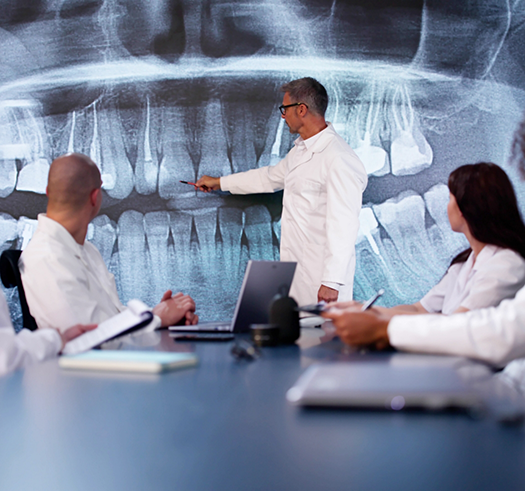 Dentist giving a presentation of an x ray of teeth to other dentists