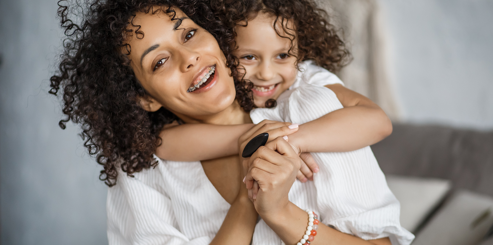 Woman with traditional braces hugging her young daughter