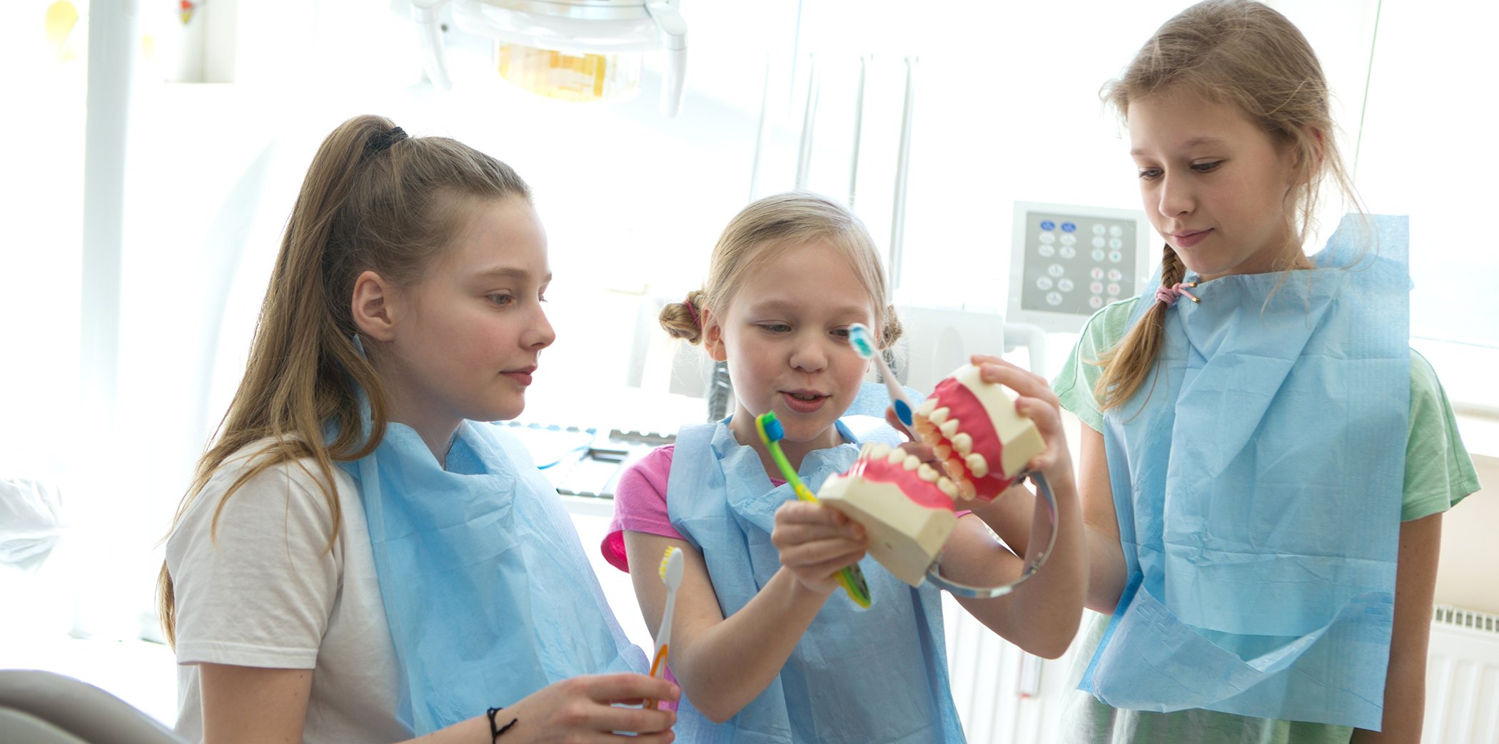 Three young girls looking at a model of the teeth while visiting pediatric dentist in Bartlett
