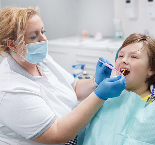 Child in the dental chair having fluoride applied to their teeth