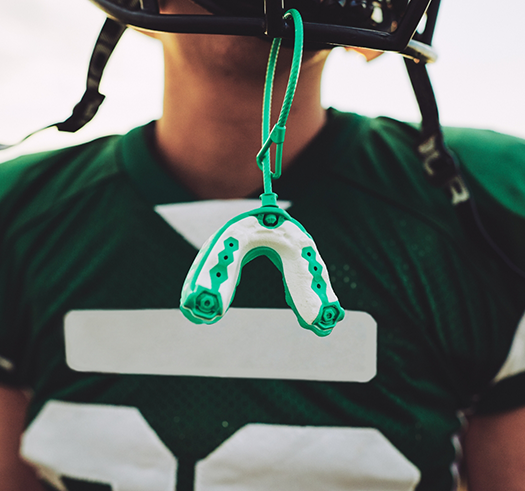 Football player with a mouthguard attached to their helmet