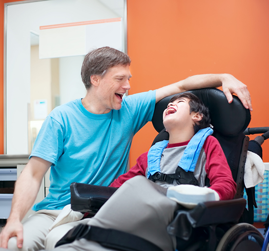 Pediatric dentist talking to a young boy patient in a wheelchair