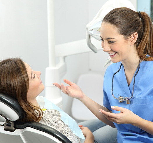 Smiling dentist talking to a woman in the treatment chair